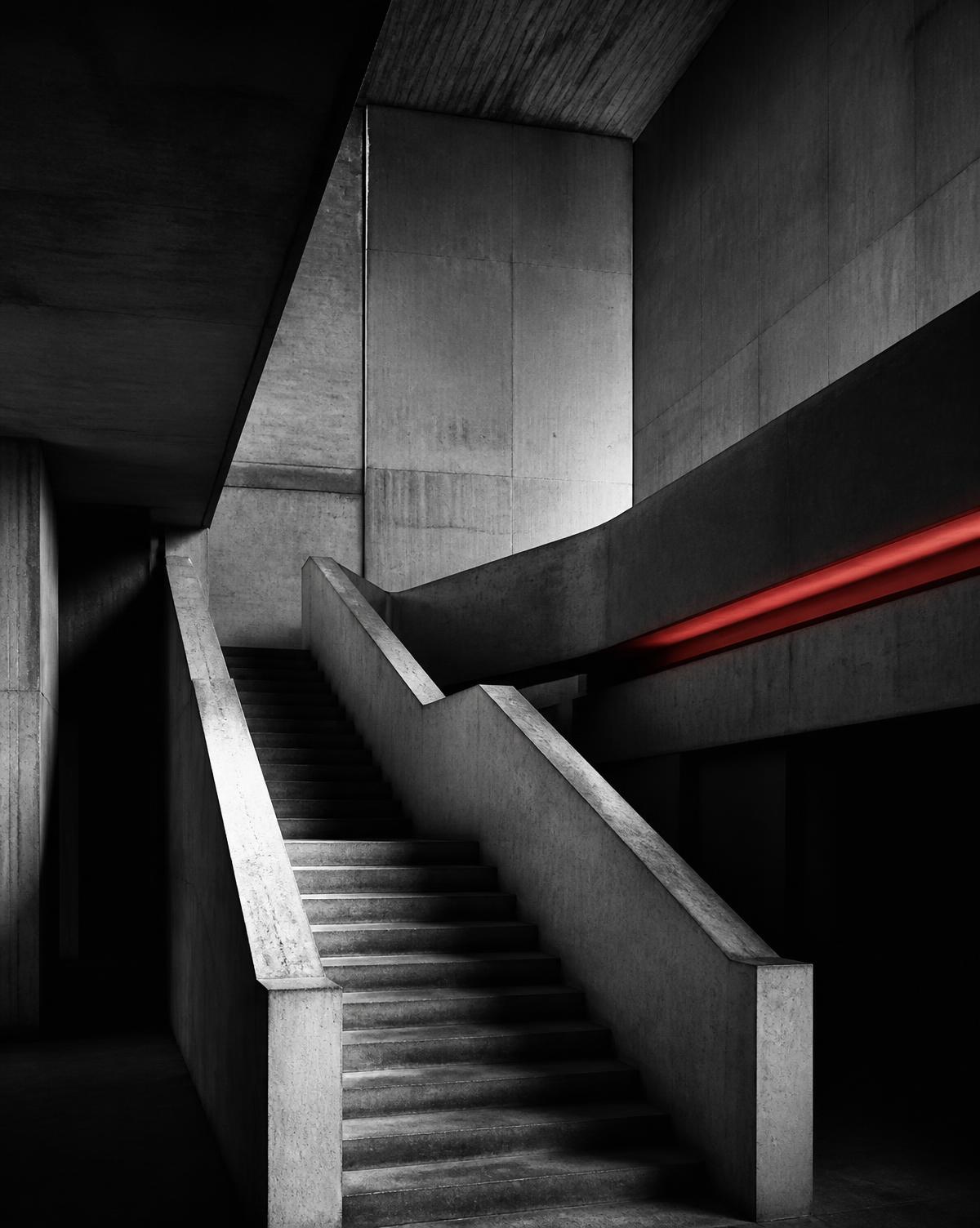 Brutalist concrete staircase with a single ember-red light strip
