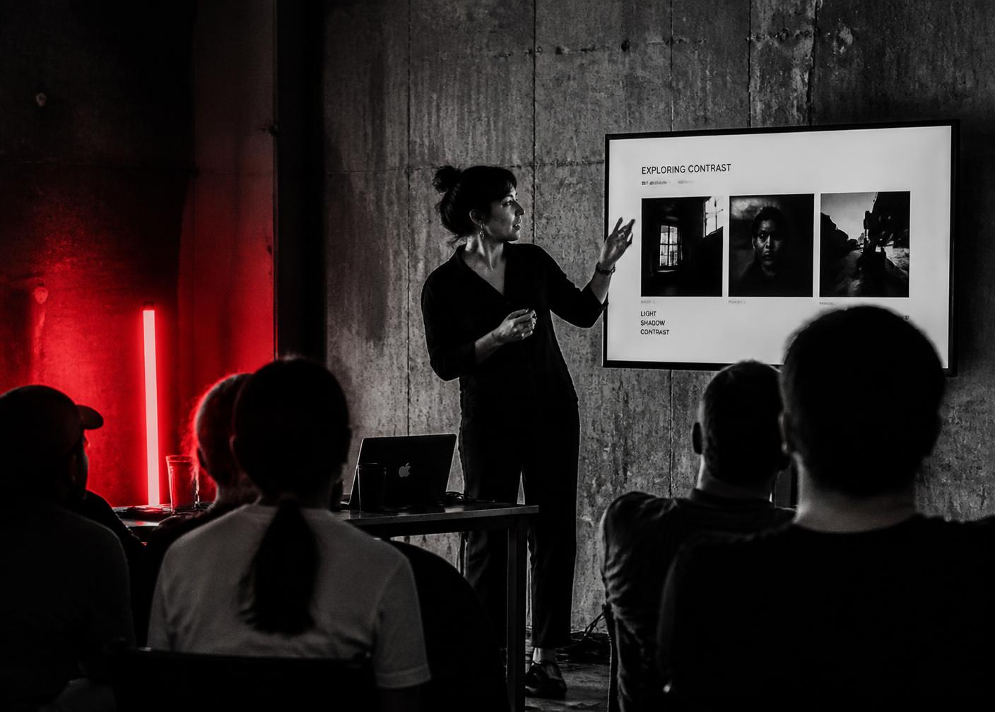 A woman teaching a workshop session in a raw concrete studio